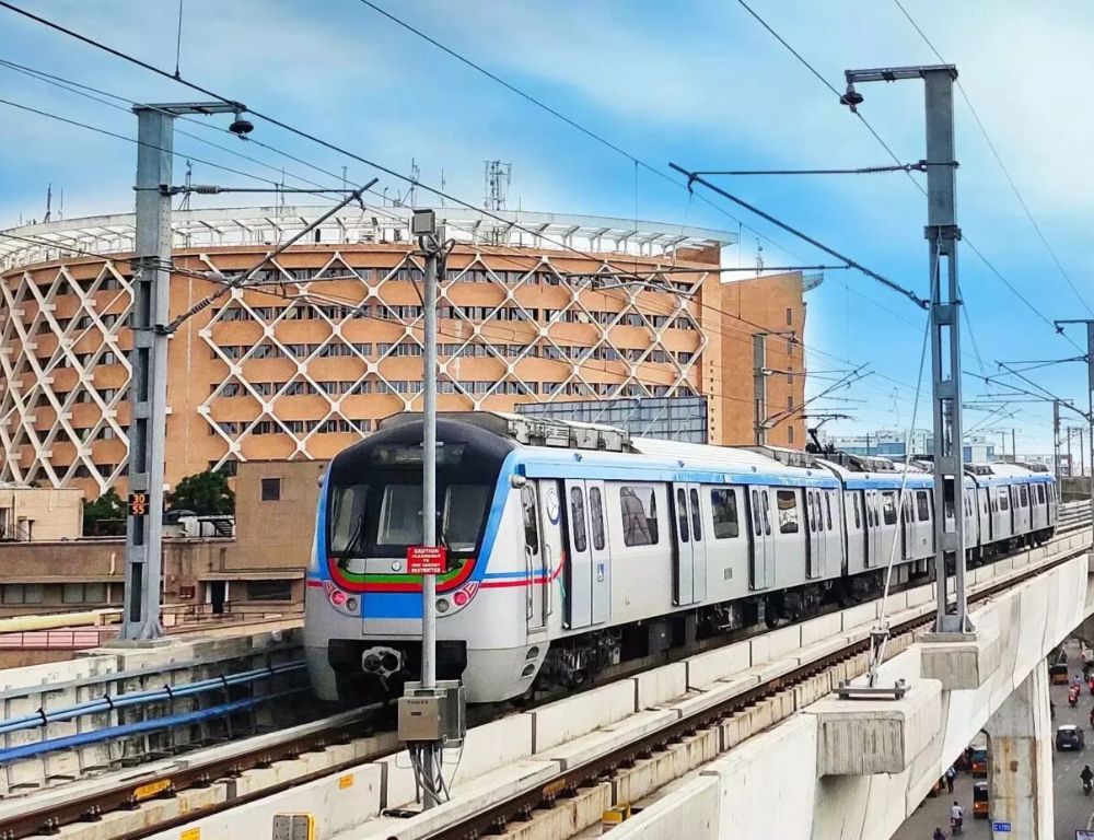 Hyderabad Metro train on an elevated viaduct beside a city building